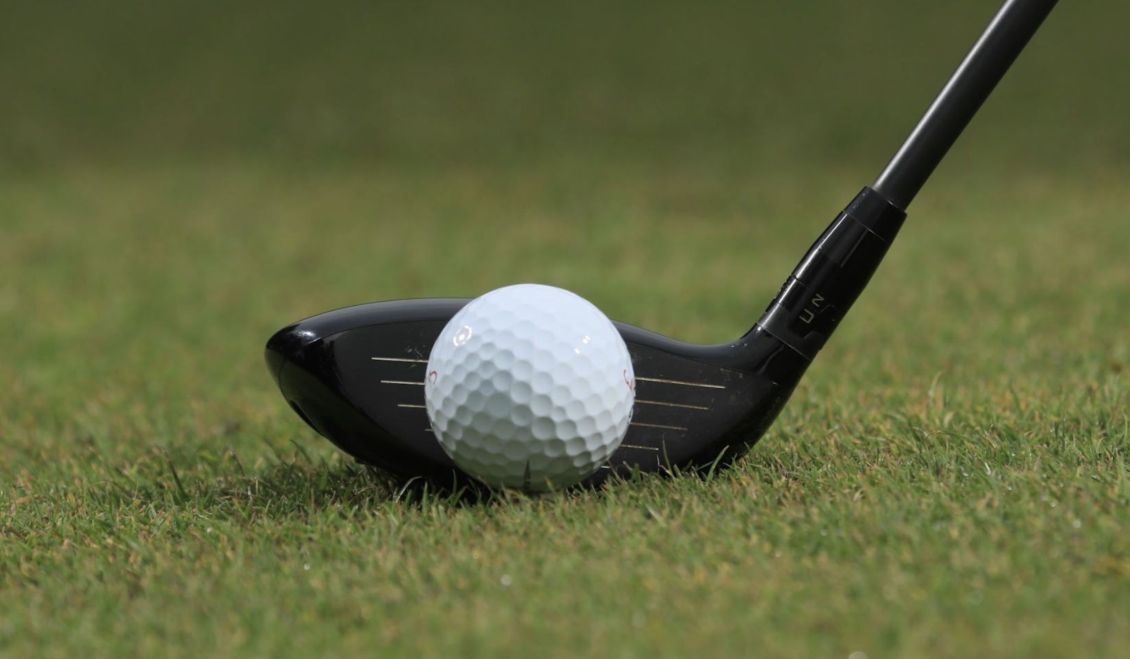Close up of a fairway wood behind a golf ball