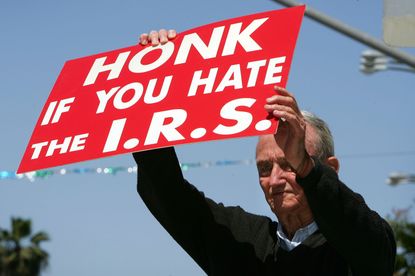 A man holds a sign that reads "Honk if you hate the I.R.S."