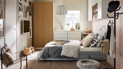 A bedroom with a grey upholstered bed and wooden floors