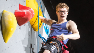 Matthew Phillips looking down from a climbing wall