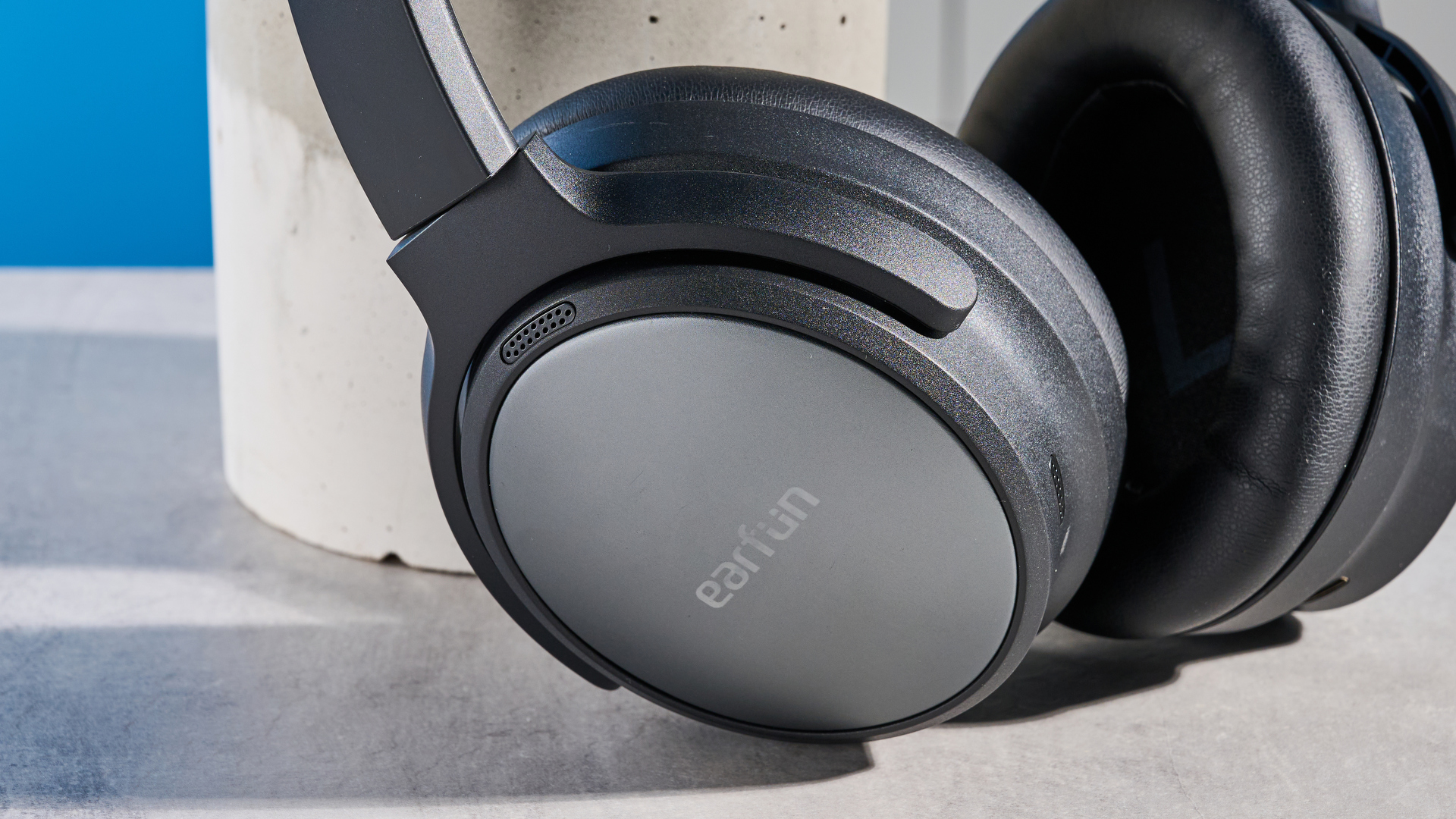 the earfun tune pro headphones, in black, with soft pleather cups, and gray cups, photographed against a blue background