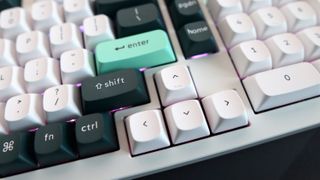 A Keychron Q5 HE gaming keyboard on a desk with white and blue keycaps.