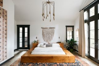 bedroom ideas with bed on a raised wooden plinth and woven wall hanging