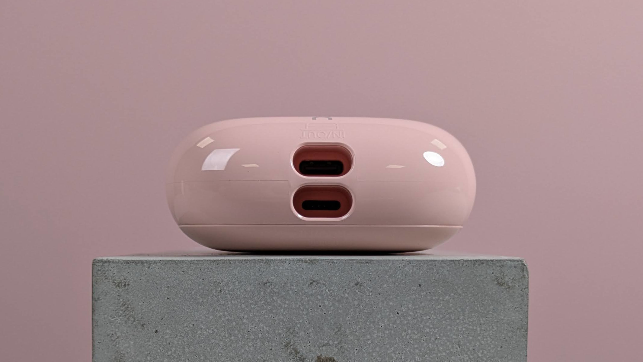 Close-up of ports on VRURC T6S power bank, on plinth with pink background