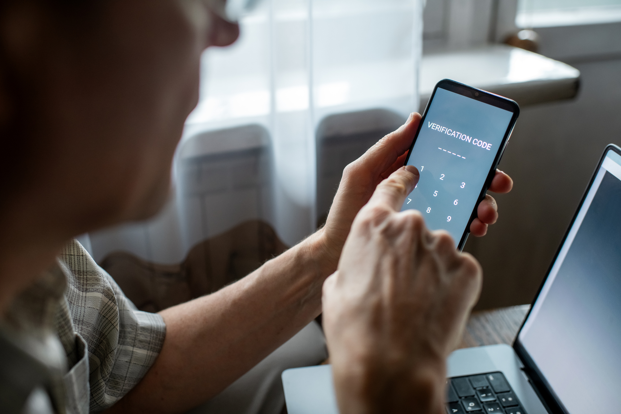 A man taps a verification code into a phone.