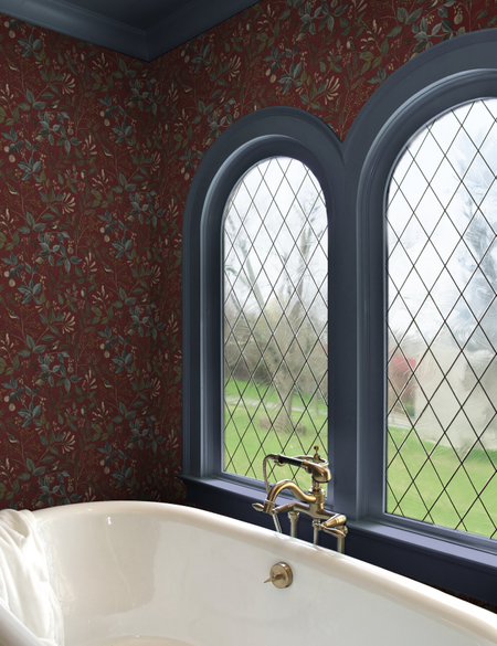 Bathroom vignette featuring a clawfoot tub situated beneath double-arched windows, which are layered with peel-and-stick diamond grid window film