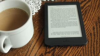 Kobo eReader on a wooden table next to a white coffee mug