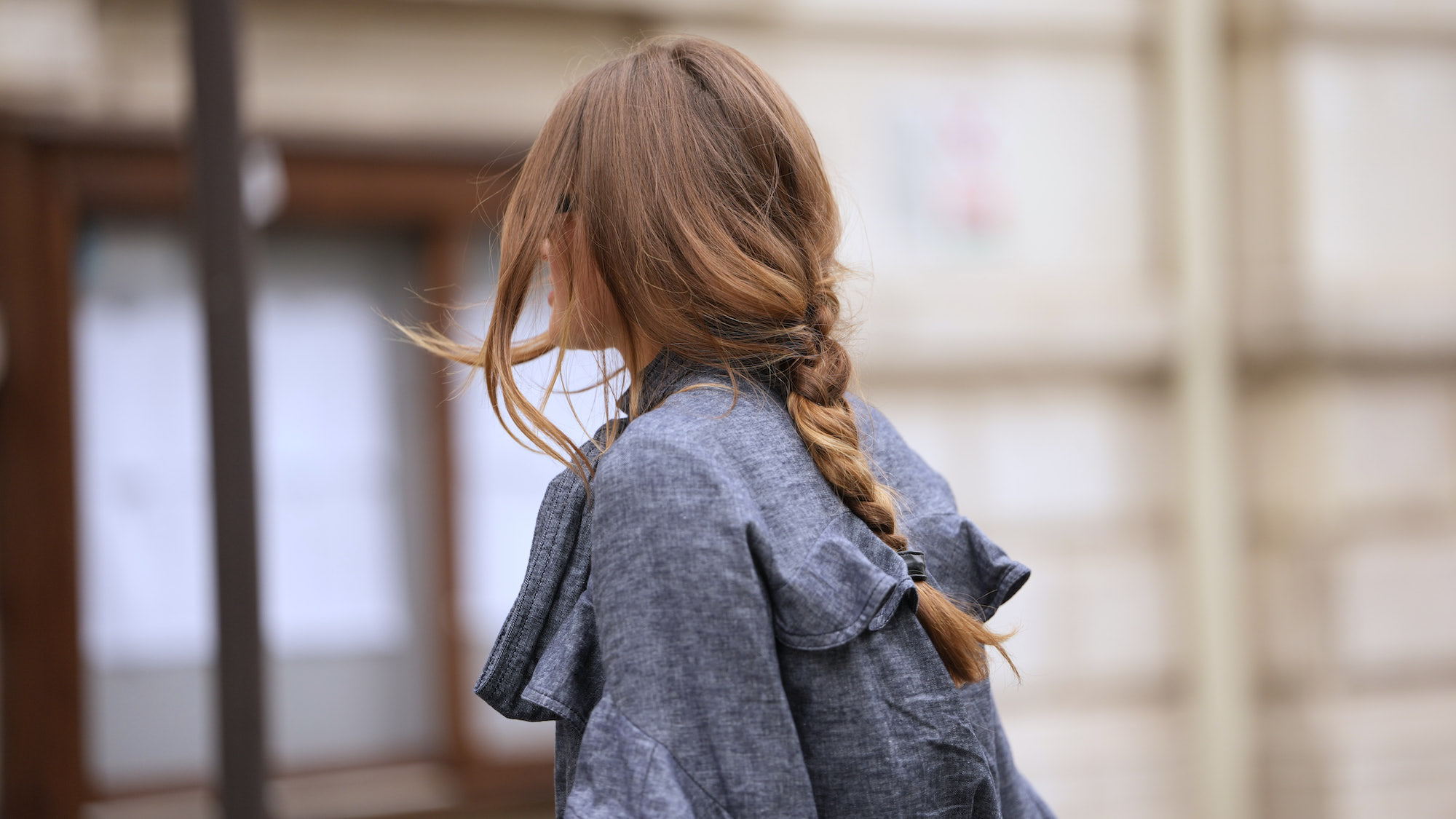woman wearing denim trench with loose middle plait - different types of hair damage and how to treat it