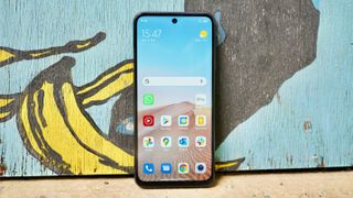 A Xiaomi Redmi Note 10 5G from the front, leaning against a wall