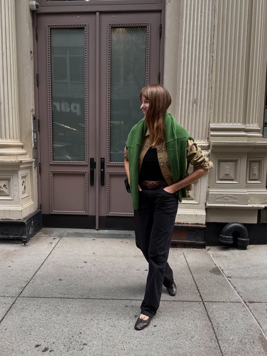 Lizzy in jeans, ballet flats and knit around her shoulders