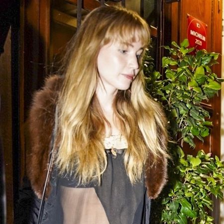 Jennifer Lawrence wearing a fur-trimmed coat, sheer top, baggy jeans, and leopard-print shoes in Paris