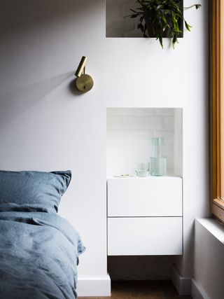 White bedroom with bed bedding and recessed shelving
