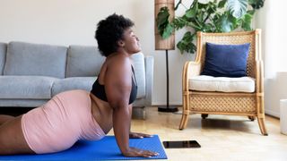 Woman practising Pilates for weight loss in front room on a blue yoga mat