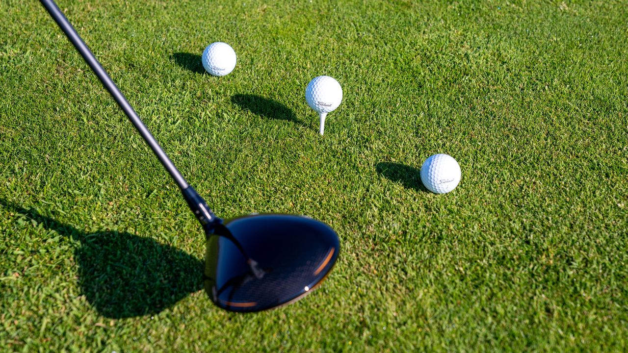 How To Stop Cutting Across The Golf Ball: A driver behind three golf balls on tees