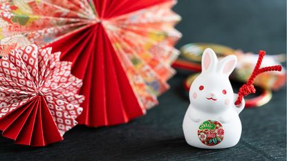 A rabbit knickknack sits next to some ornate paper fans.