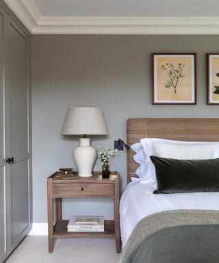 bedroom with gray walls, patterned headboard, wooden bedside table, green velveet cushions and wooden bedside table