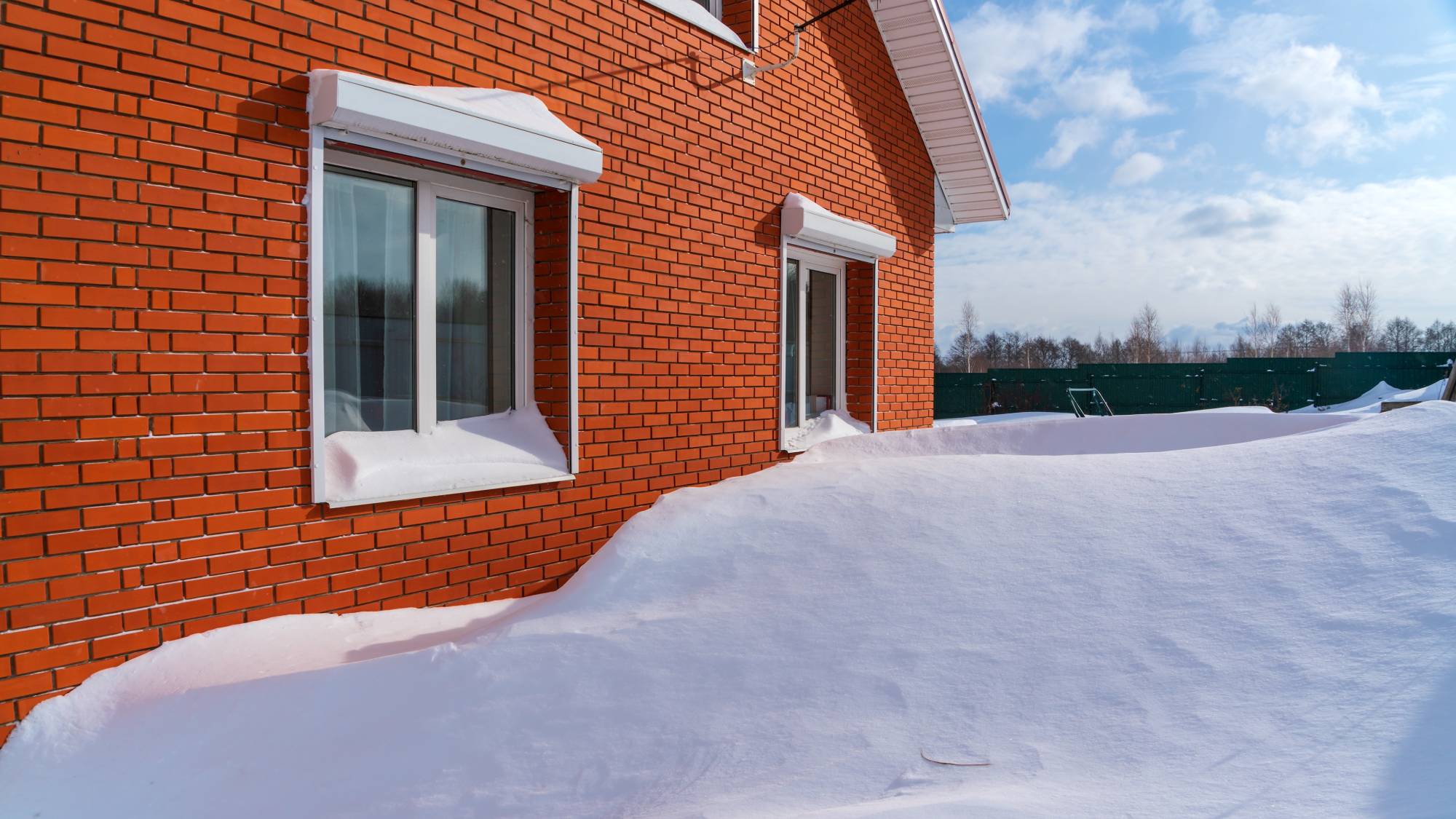 Snowdrifts against a red brick house