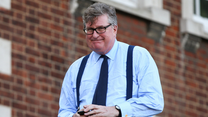 Crispin Odey walking holding his phone