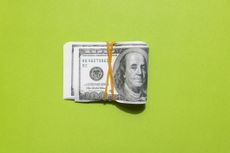 Several one hundred dollar bills bundled on a green background