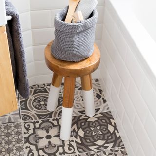 A bathroom with a stool and patterned floor tiles