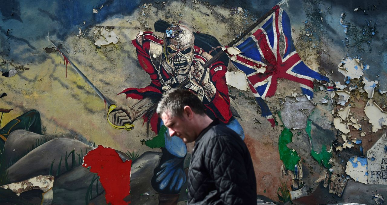 A man walks past a mural marking unionist territory