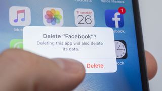 Picture of a thumb hovering over a smartphone screen showing the user is about to delete the Facebook app