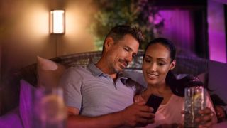 Couple looking at phone in front of Philips Hue Impress wall light