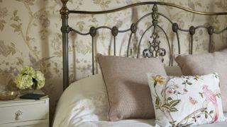 Headboard with cast iron headboard, floral cushions and white bedlinen