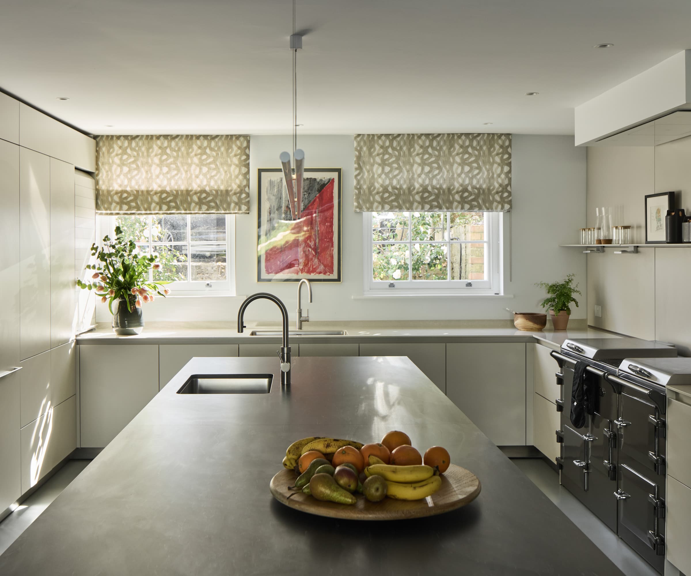 A kitchen island with a sink in built and a black kitchen oven to the side