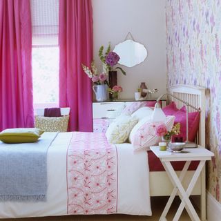 bedroom with pink curtains and pillows on bed