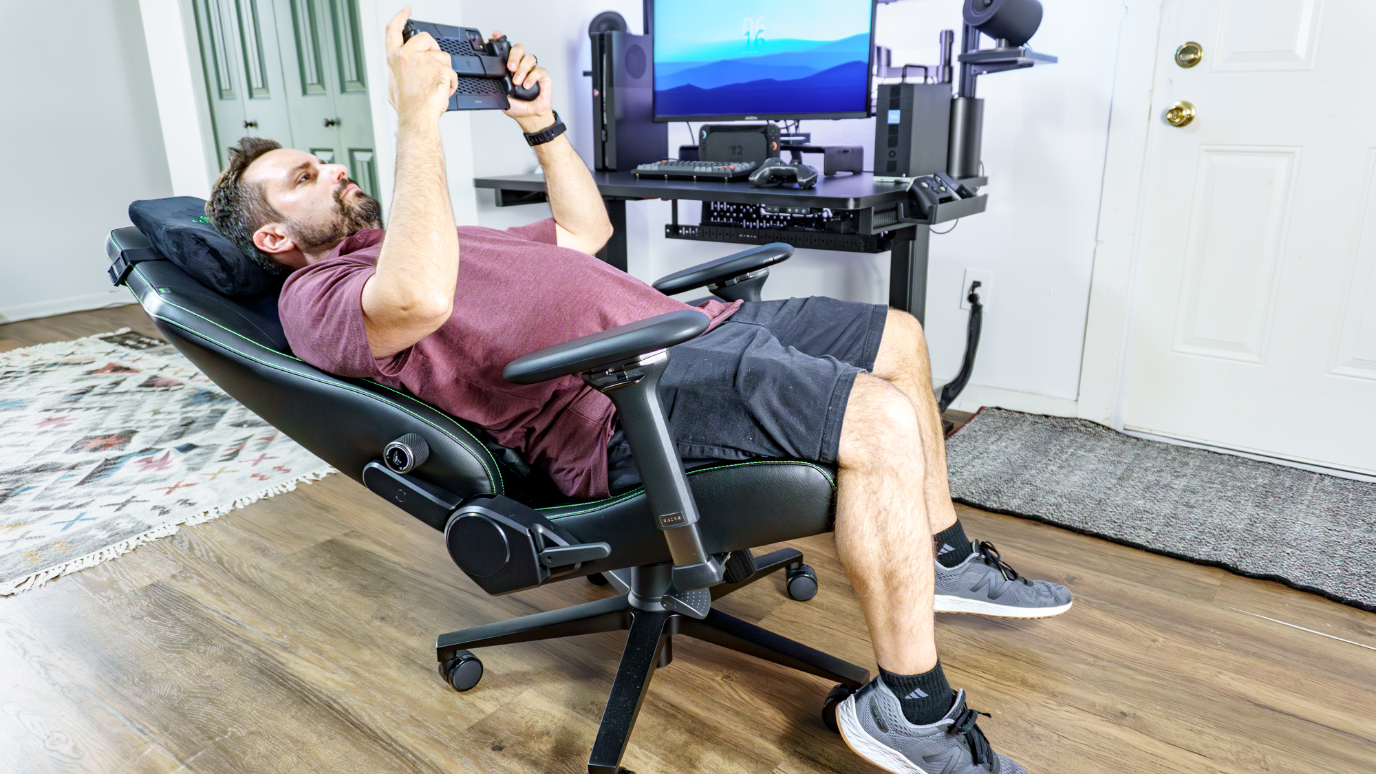 A person fully reclined in the Razer Iskur V2 NewGen gaming chair playing games remotely on a tablet using the Razer Kishi Ultra mobile game controller