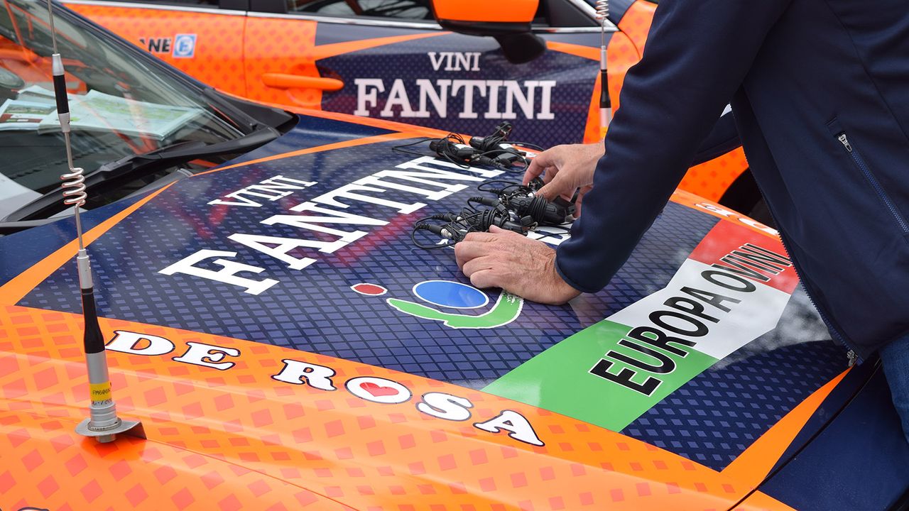 A Nippo Vini Fantini directeur lines up the team radios ahead of a stage start