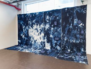 The clay-festooned, tie-dyed denim wall installation