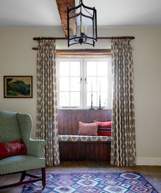 beamed hall with wooden windowseat, block printed curtains, green armchair and patterned rug