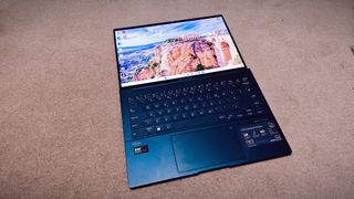 A blue ASUS Zenbook 14 OLED (UX3405) on a carpeted floor