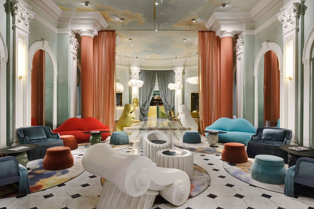 An imaginatively designed hotel's common areas feature otherworldly d&eacute;cor, including sky-like floors, pink arches and curtains, and sculptural furniture.