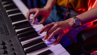 Close up of Musician Hands Playing Synthesizer Keyboard in Neon Lighting. Artist Producing Music in Home Studio, Recording Audio with Professional Equipment. Creative Arts and Hobby Concept.