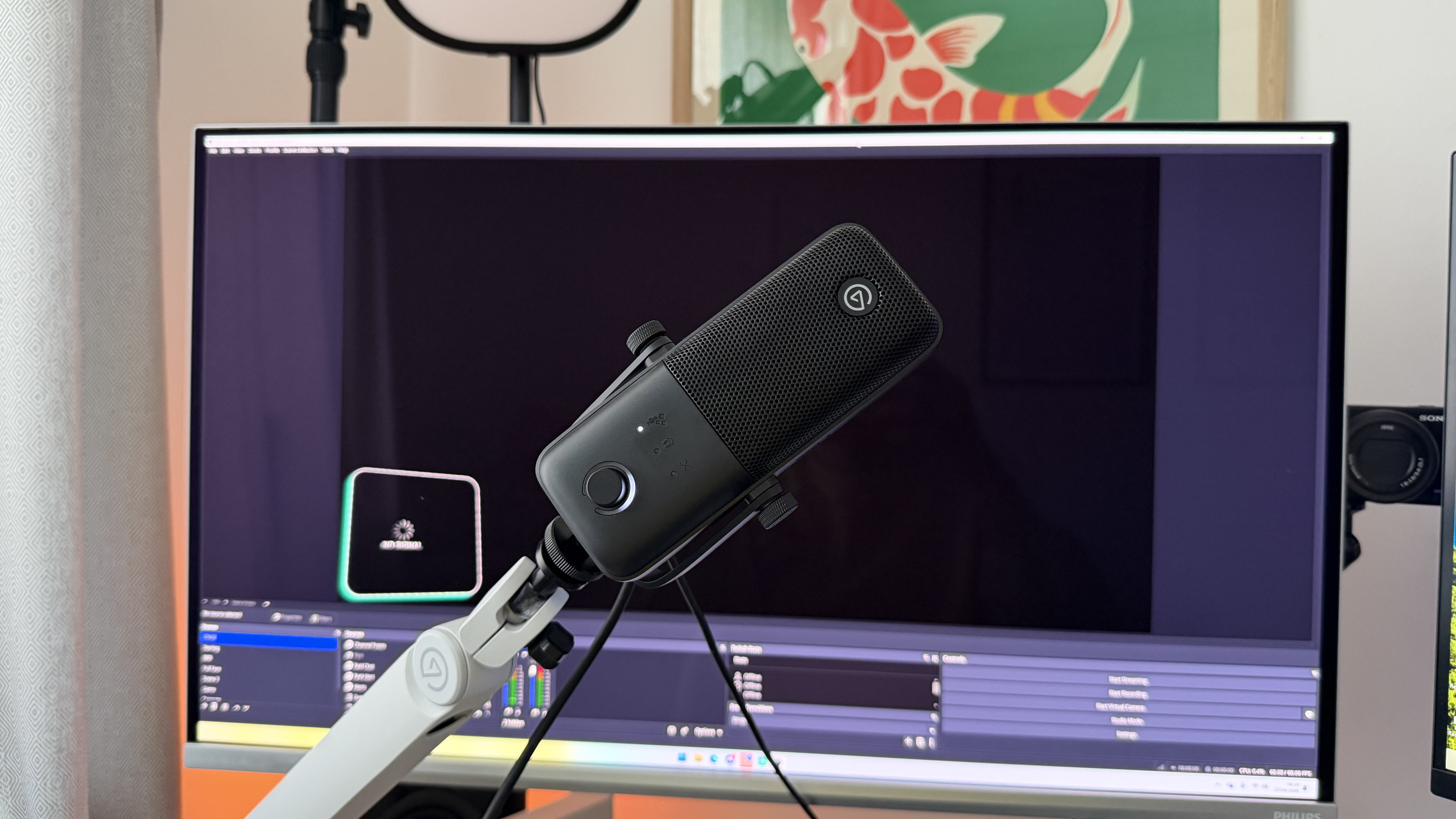 An Elgato Wave 3 Mk2 on a boom arm in front of a monitor displaying OBS