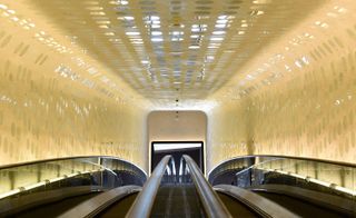Visitors enter the concert hall via a gently curving escalator with gold walls.