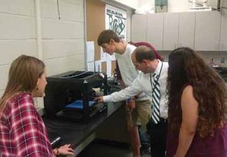 An instructor reviews student-designed 3D printed golf grips. 