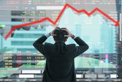 businessman holding head looking at troubling stock market chart