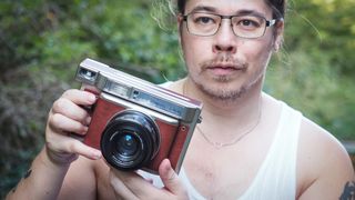 James Artaius holding a Lomo'Instant Wide Glass camera, against a woodland background