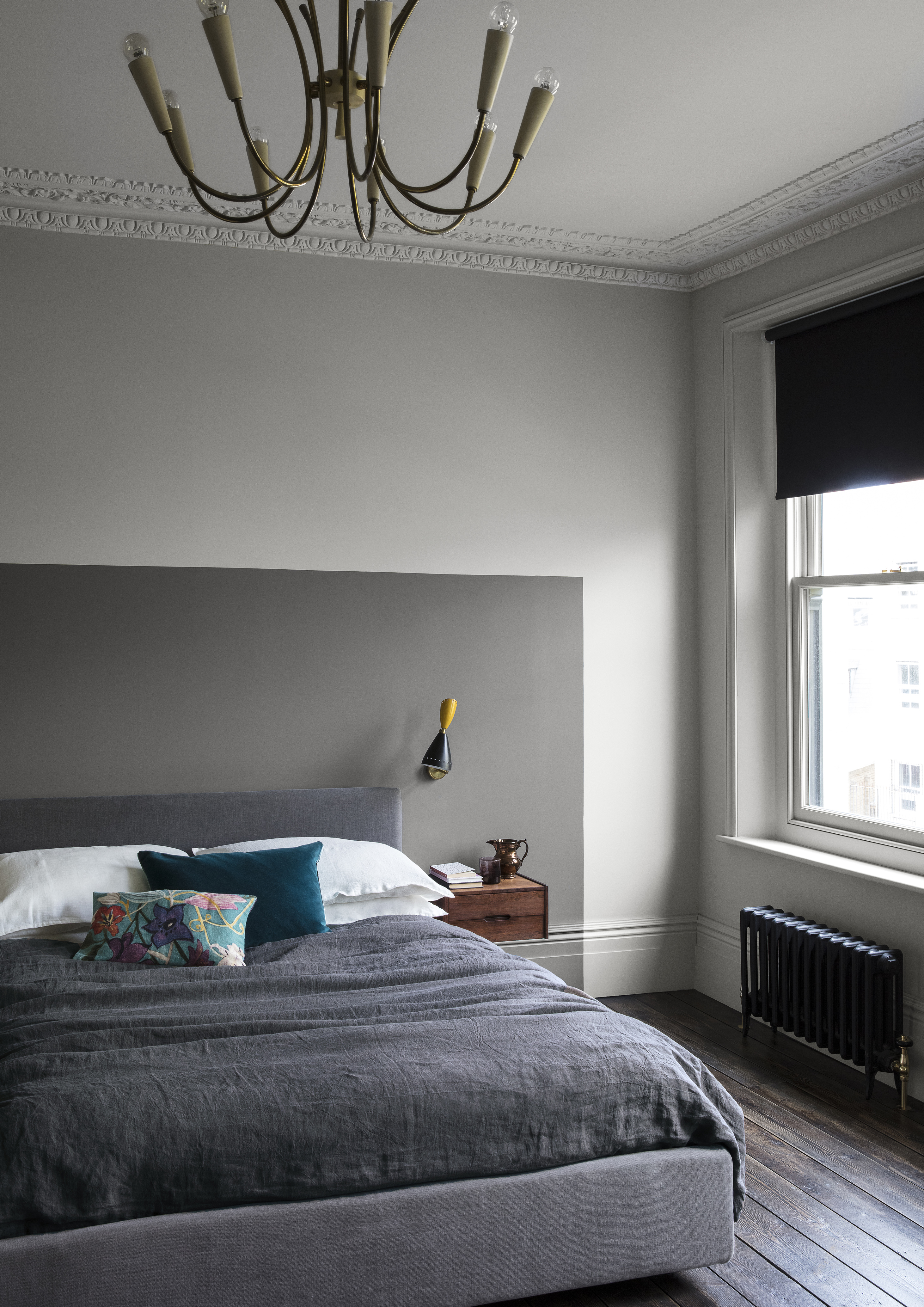 grey and white bedroom with two tone grey walls, dark wooden floor, dark grey abstract painted headboard, wall light