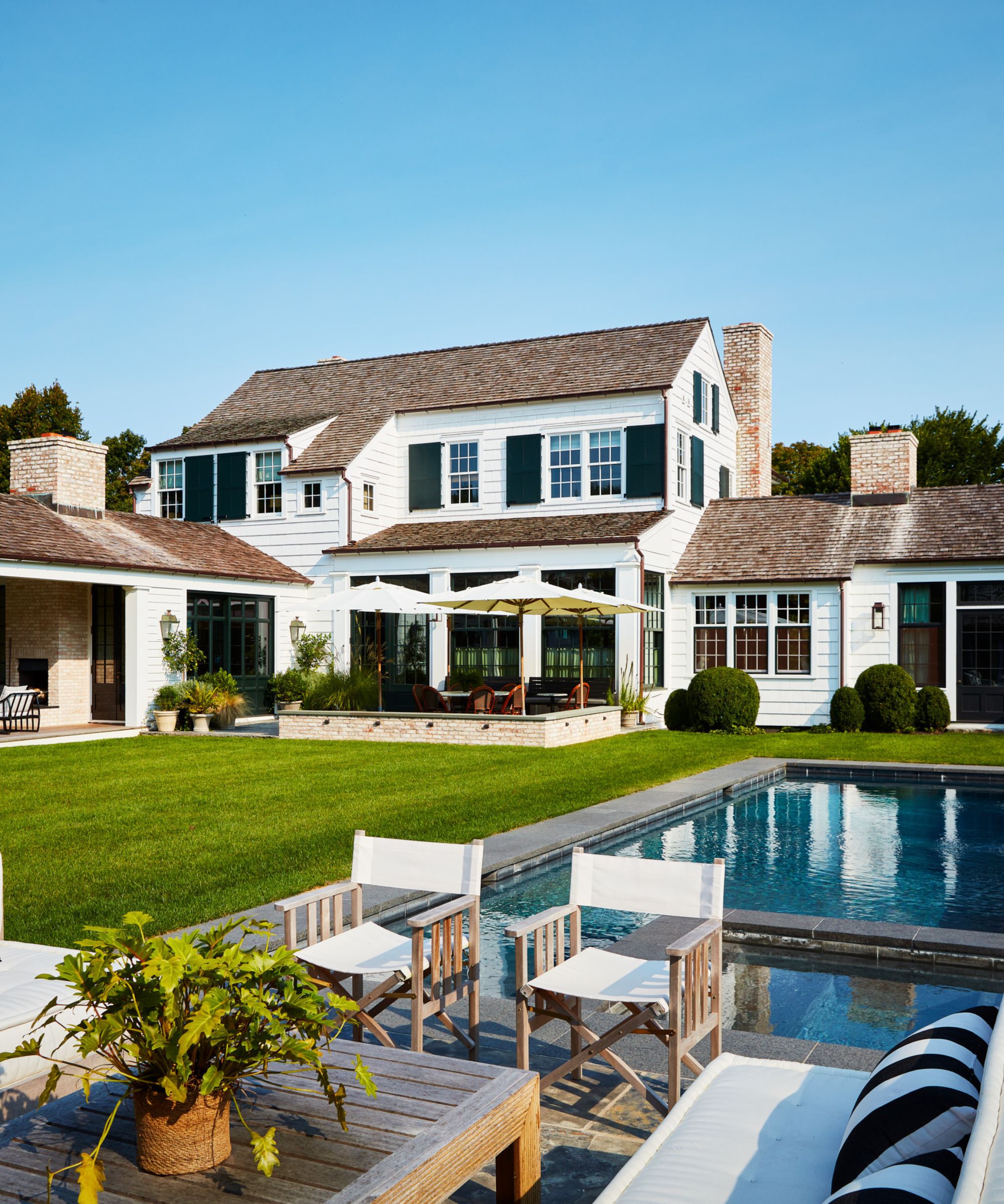 White wood-panelled house with pool in the garden