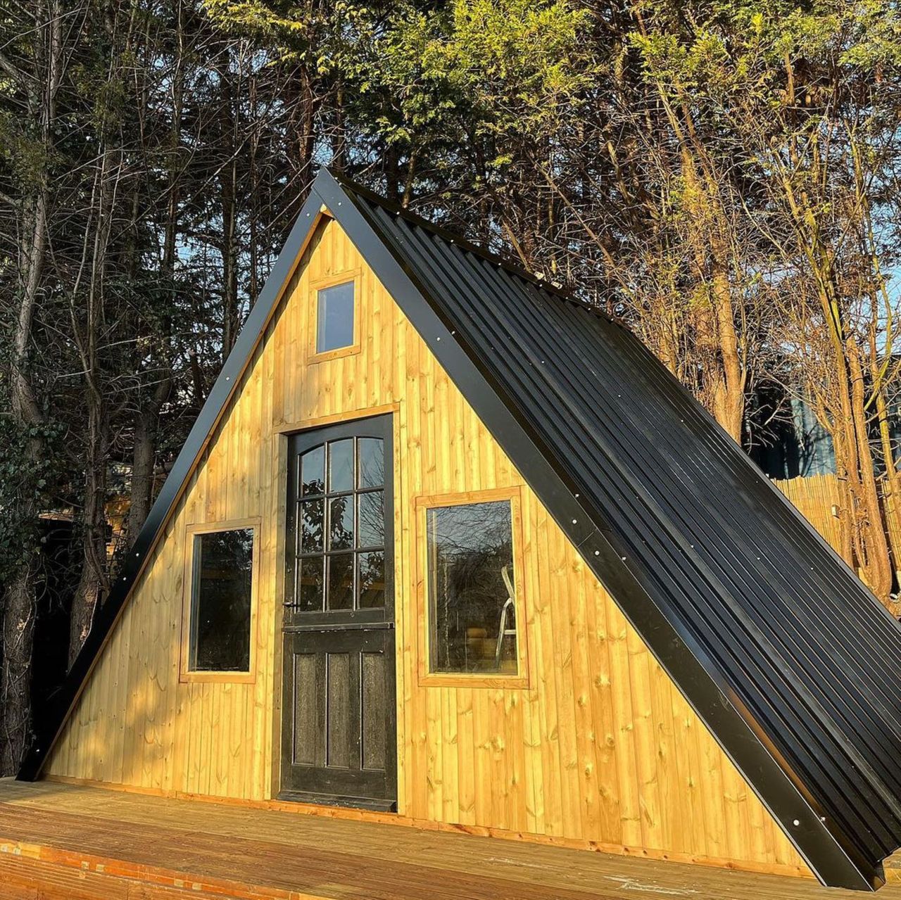 The after picture of the new shed shows a big transformation as the shed is now triangular in shape with metal sheet roofing and has a balcony