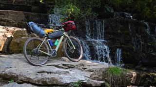 A bike set up for bikepacking in front of a waterfall