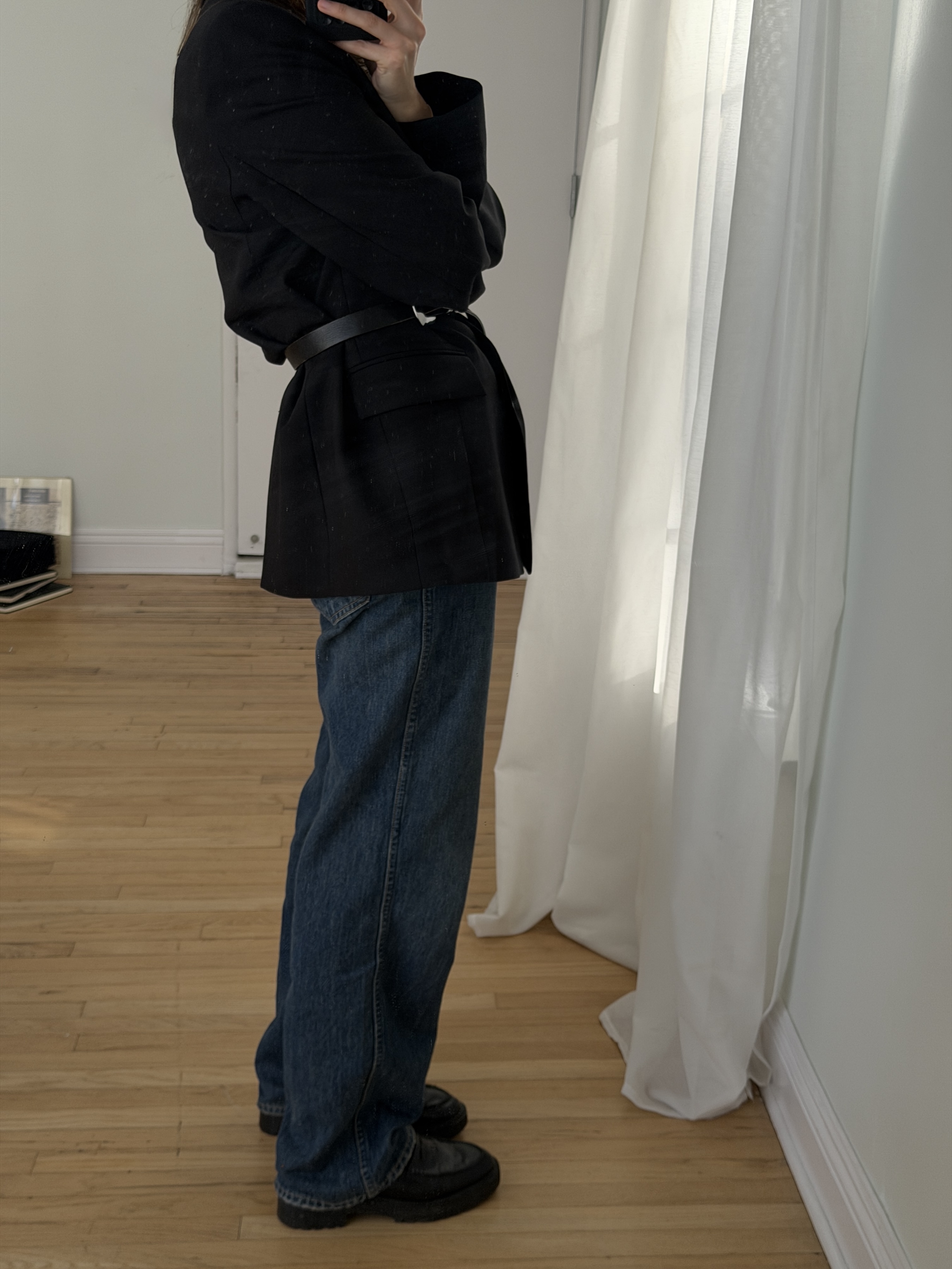 Kathryn Zahorak posing in mirror wearing black blazer, belt, baggy jeans, black boots