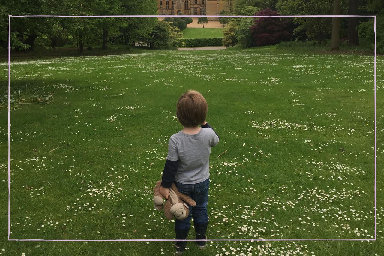 Little boy holding his teddy looking at a stately home