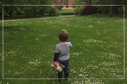 Little boy holding his teddy looking at a stately home