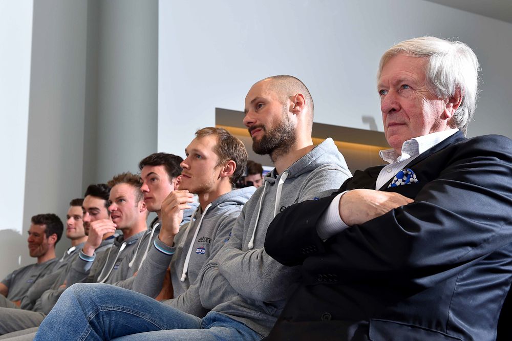 The team is lined up in the front row of the press conference.